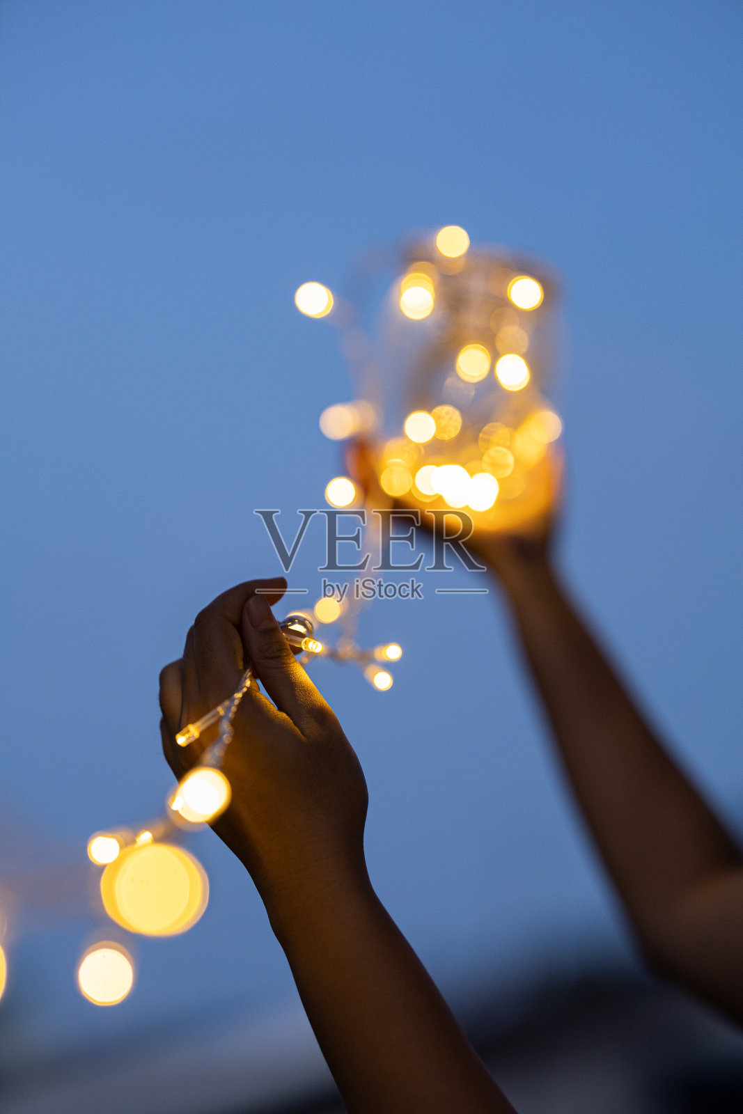 手持瓶，选择软焦点在手与前景和背景散景对天空照片摄影图片