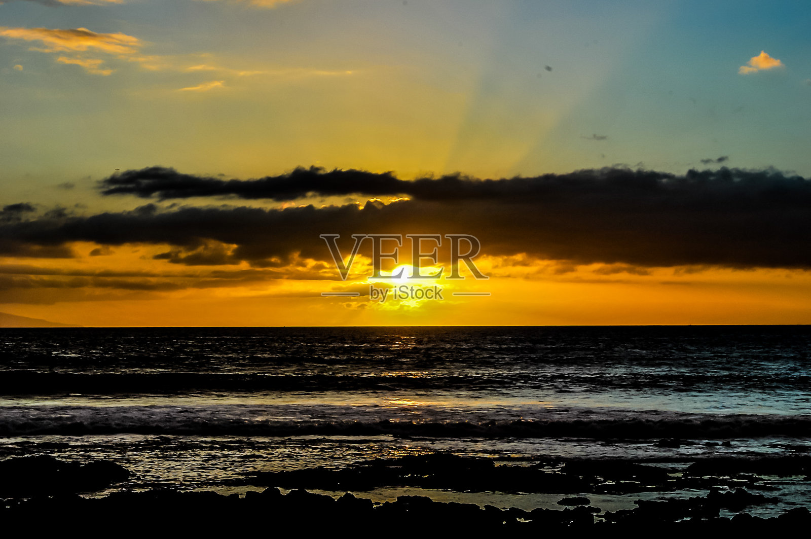 太阳正落在海面上，在水面上投下温暖的光芒照片摄影图片