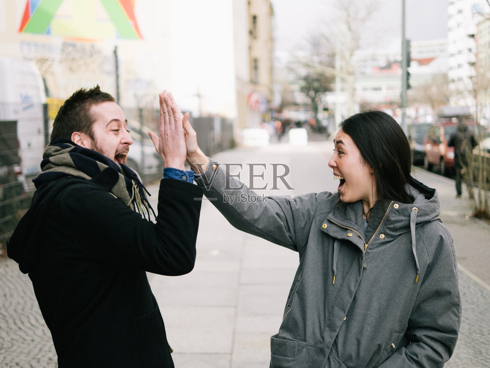 兴奋的朋友在城市的人行道上击掌照片摄影图片