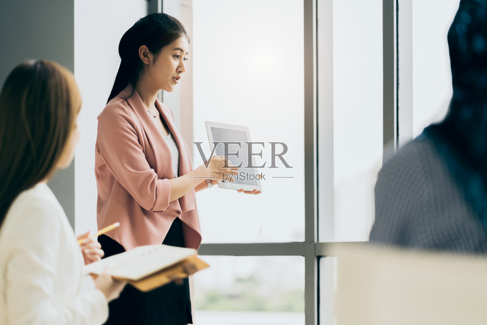 女商人在办公室用平板电脑向同事做演示照片摄影图片
