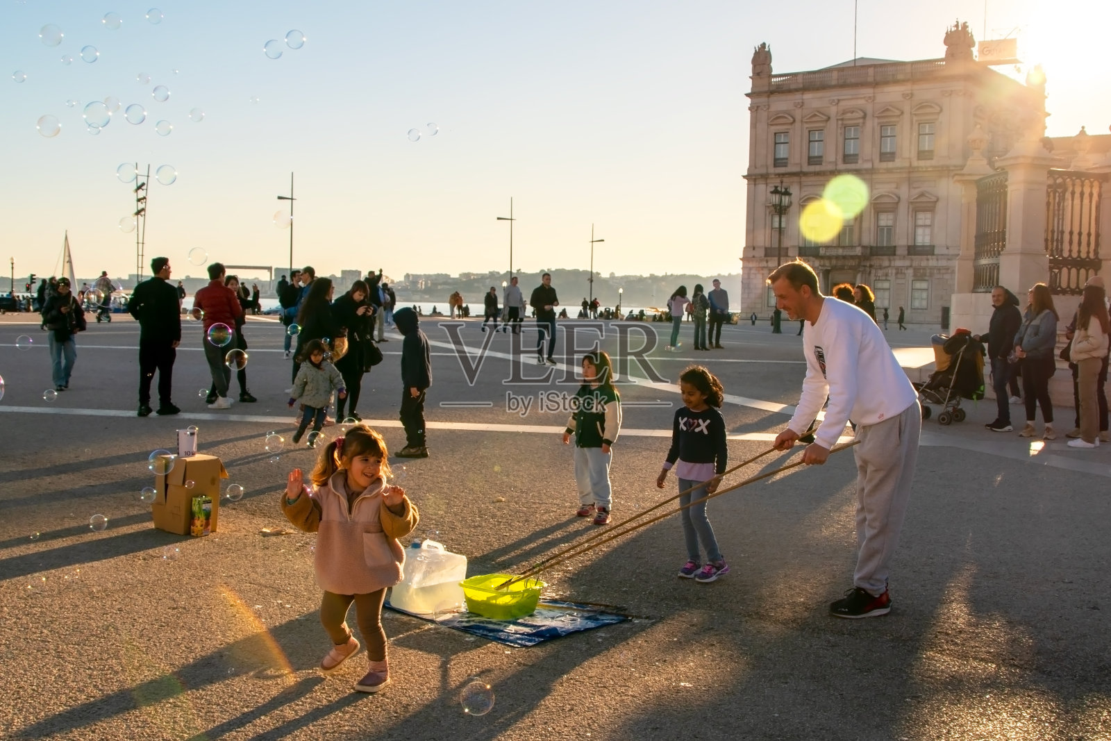 葡萄牙里斯本,孩子们在城市的主要广场上玩肥皂泡,快乐的人们享受着温暖的阳光夜晚照片摄影图片