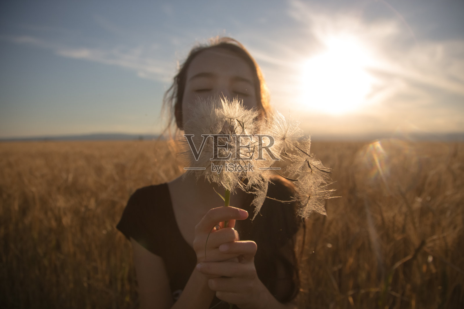 年轻女子向天空吹蒲公英照片摄影图片