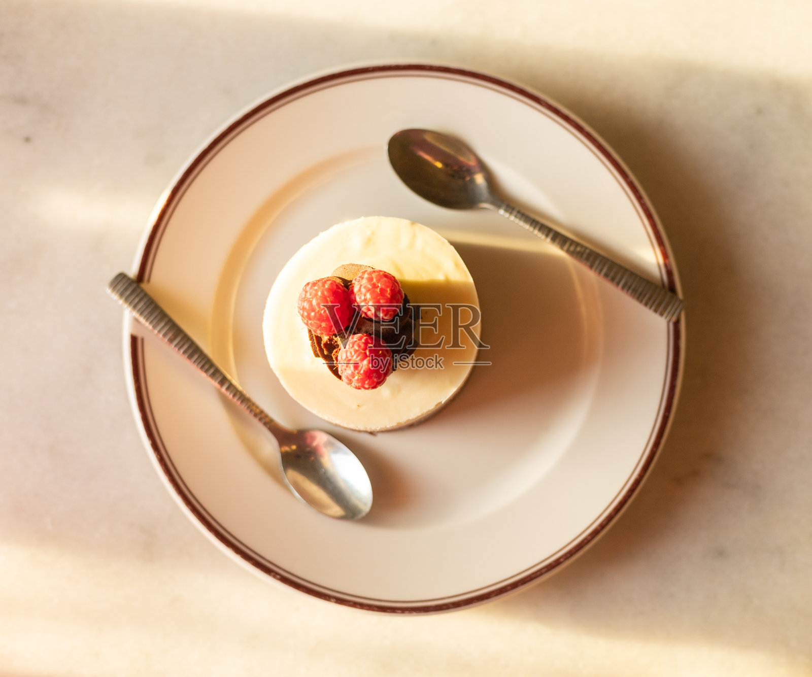 有覆盆子的甜点，一个挞和两个勺子放在盘子里，爱的概念照片摄影图片