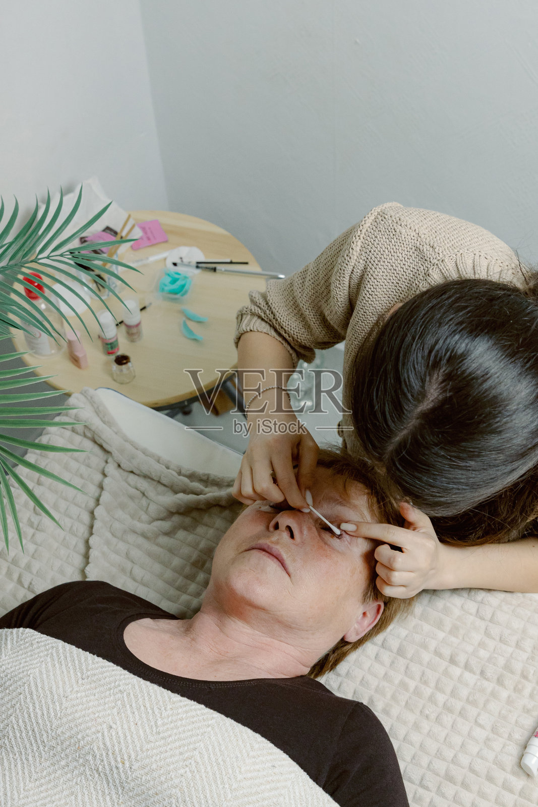 一位女美容师在给女性的睫毛贴膜。照片摄影图片