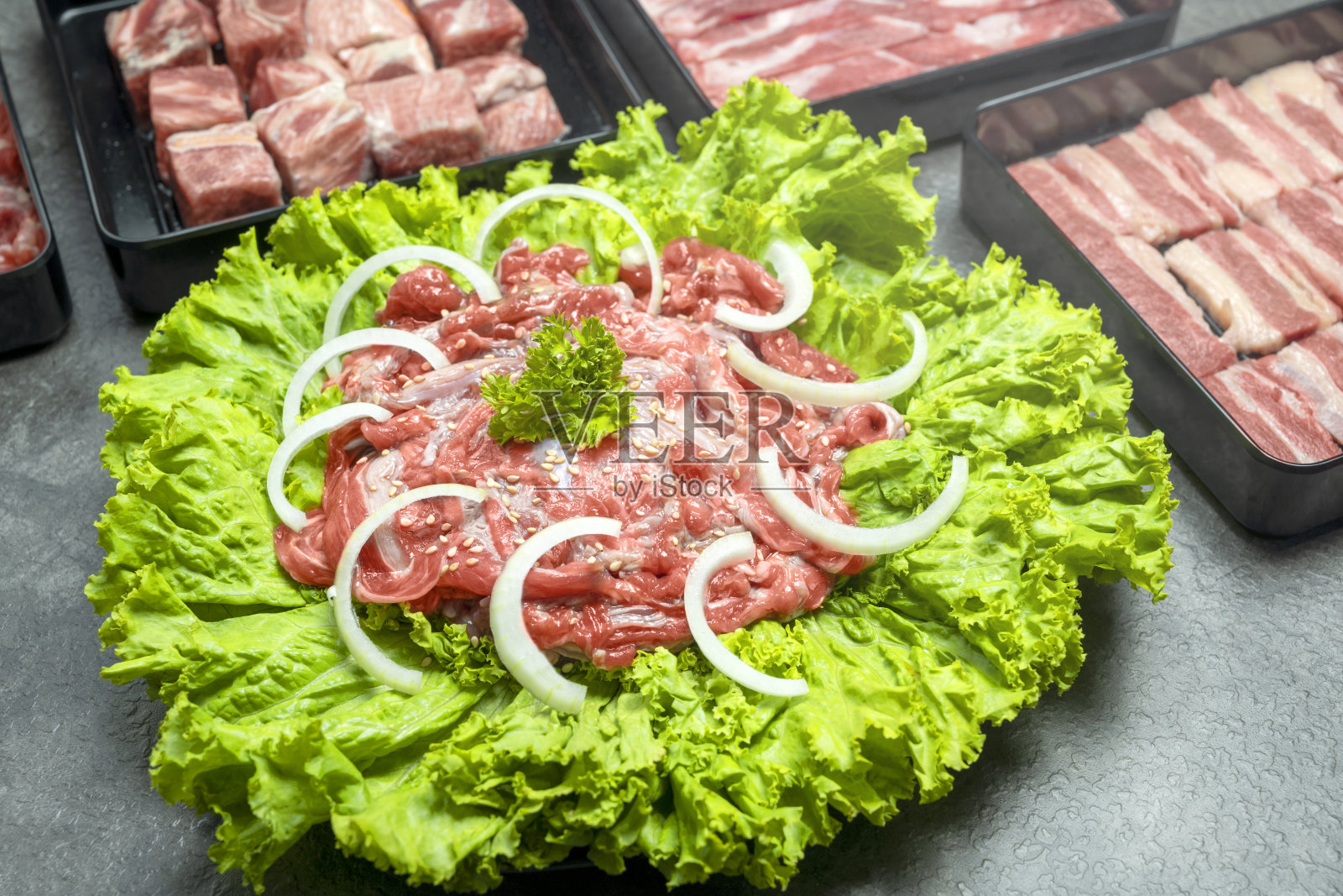 一盘肉，上面放着洋葱和生菜照片摄影图片