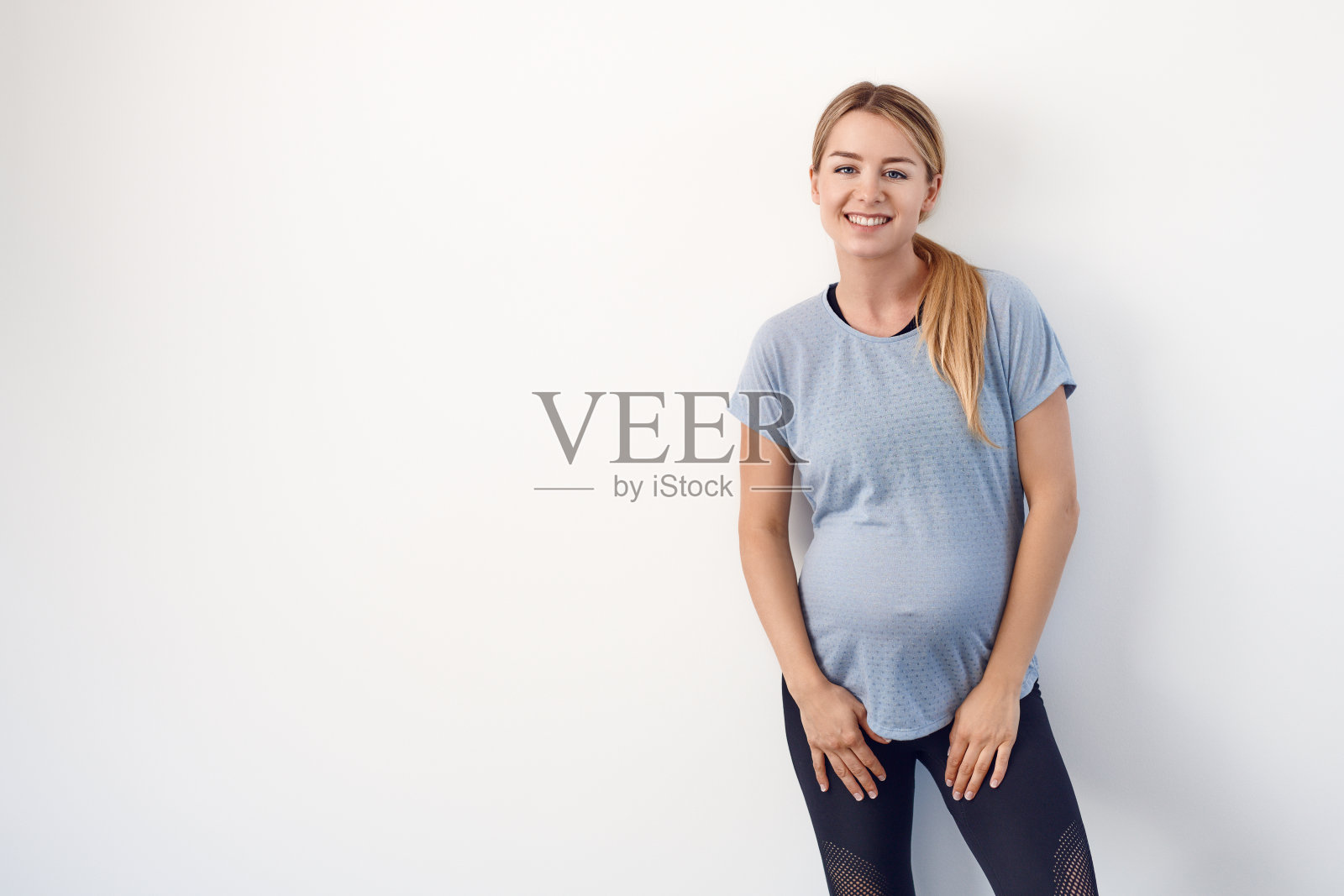 微笑的年轻孕妇站在白色背景的肖像照片摄影图片