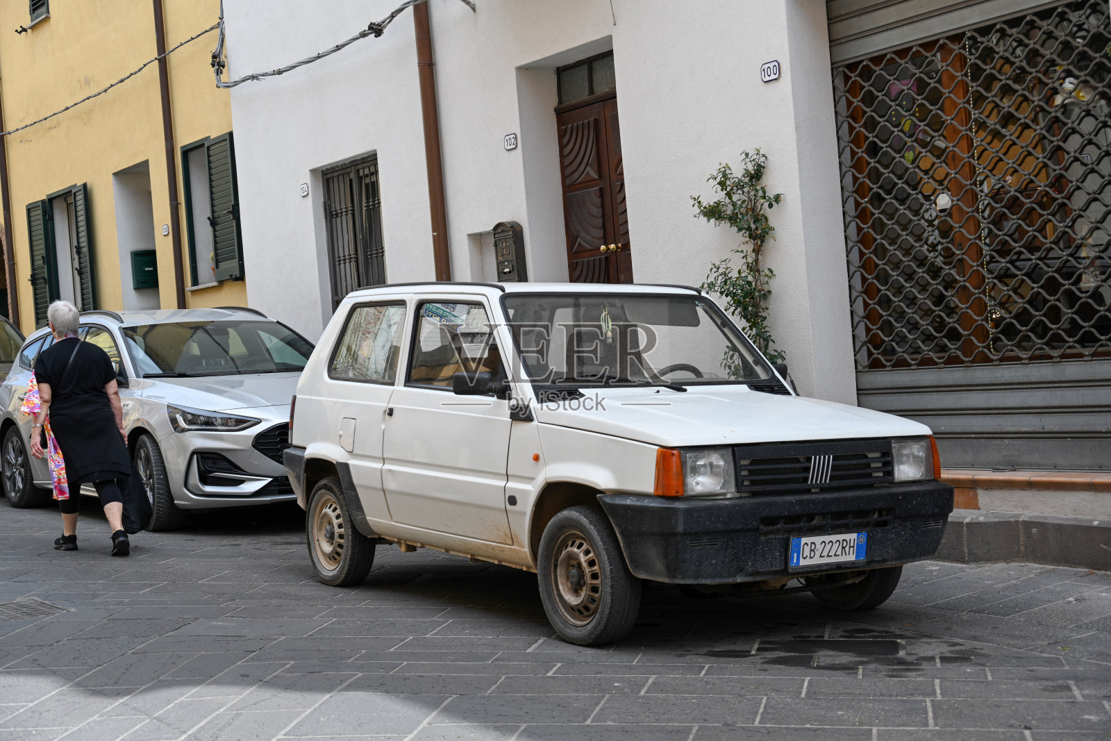 一辆白色的菲亚特熊猫停在撒丁岛奥罗塞的一条小巷上。照片摄影图片