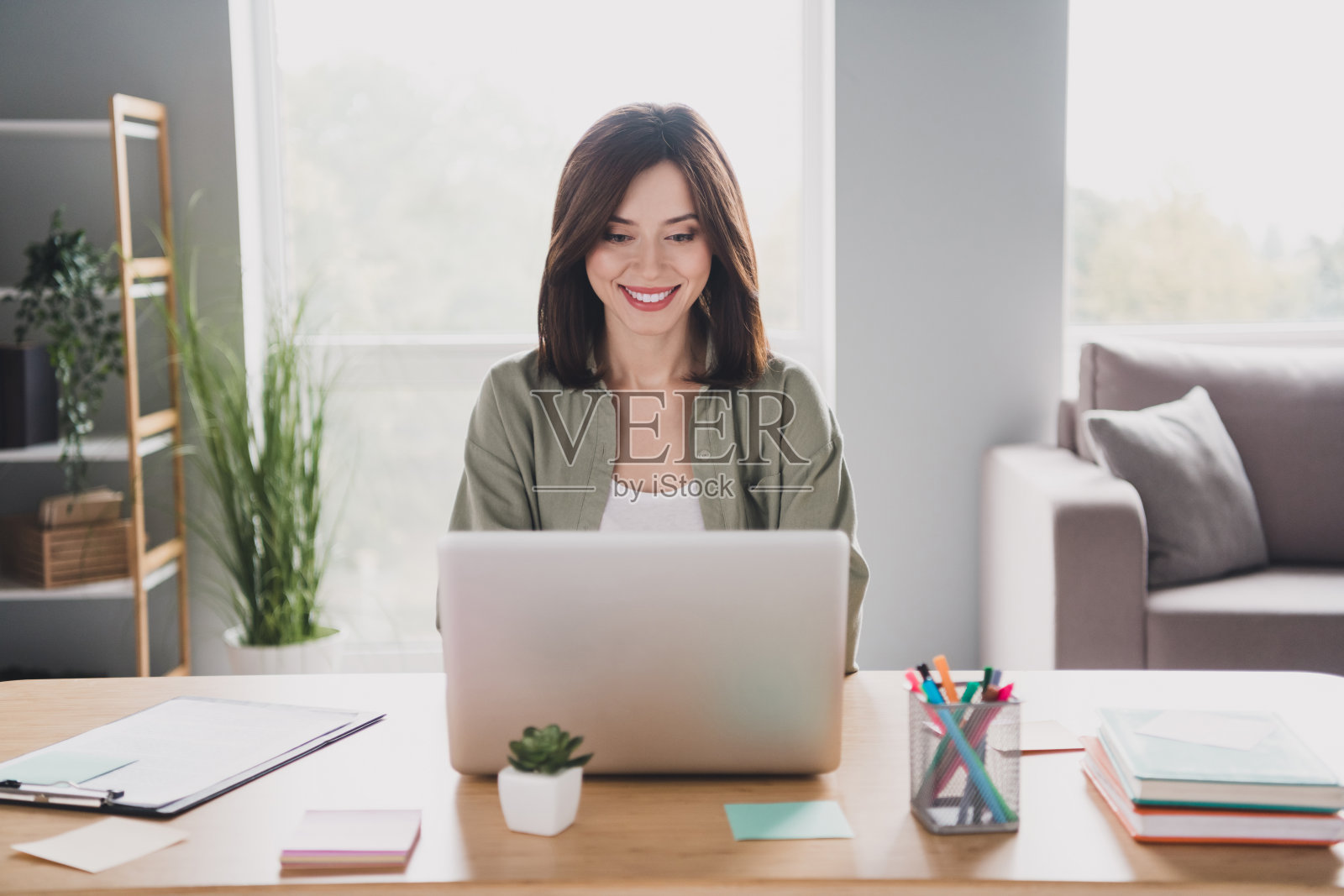 照片中，相当开朗的律师女士在现代工作场所室内使用无线上网本打字照片摄影图片