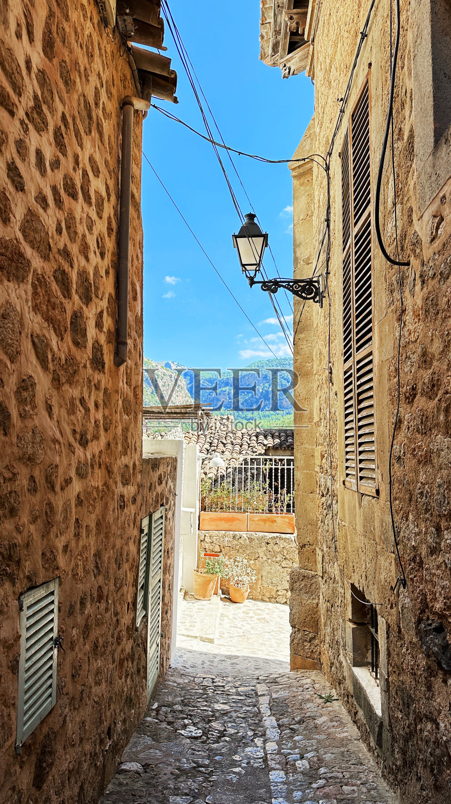 古老狭窄的欧洲街道在一个城市，与石墙，山和天空的正面视图照片摄影图片