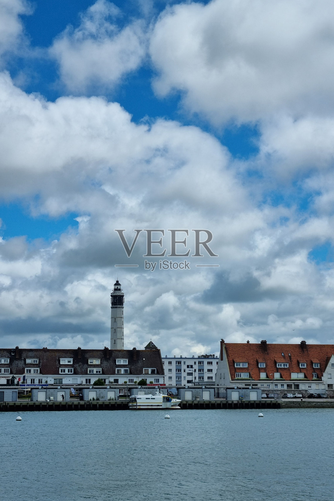 多云的天空下，风景秀丽的湖畔小镇和灯塔照片摄影图片