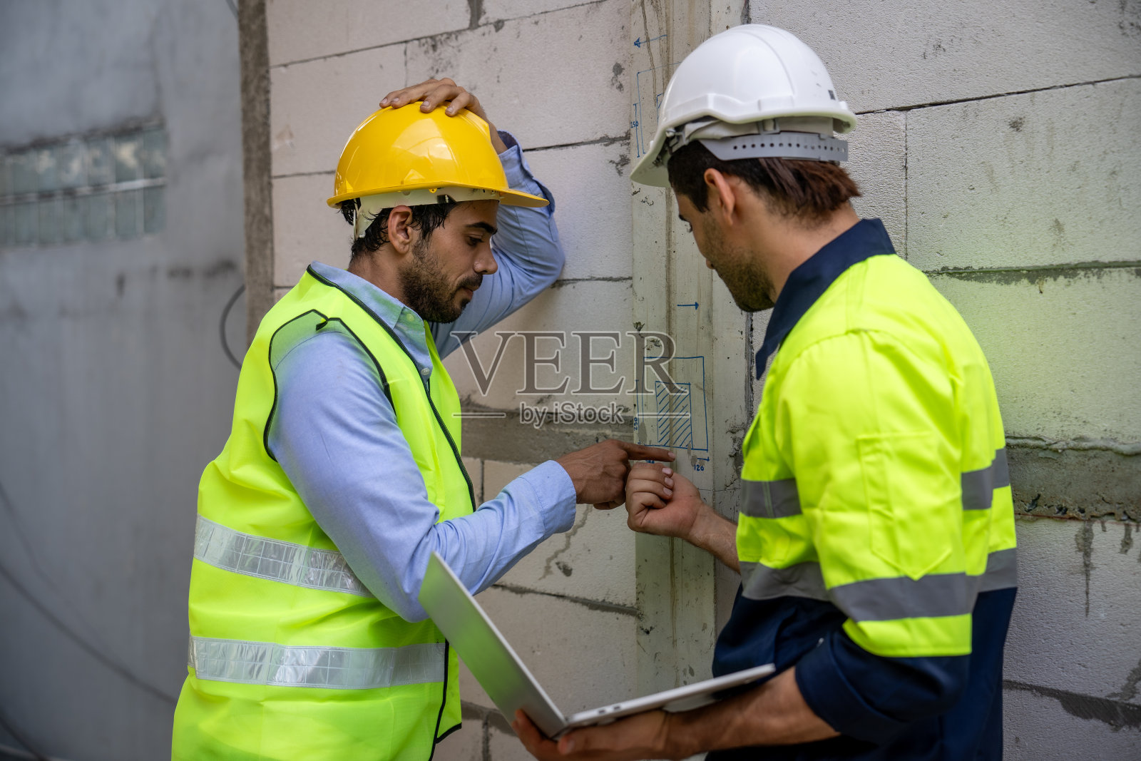 专业工程师和建筑师在建筑工地讨论施工计划，带有蓝图和笔记本电脑照片摄影图片