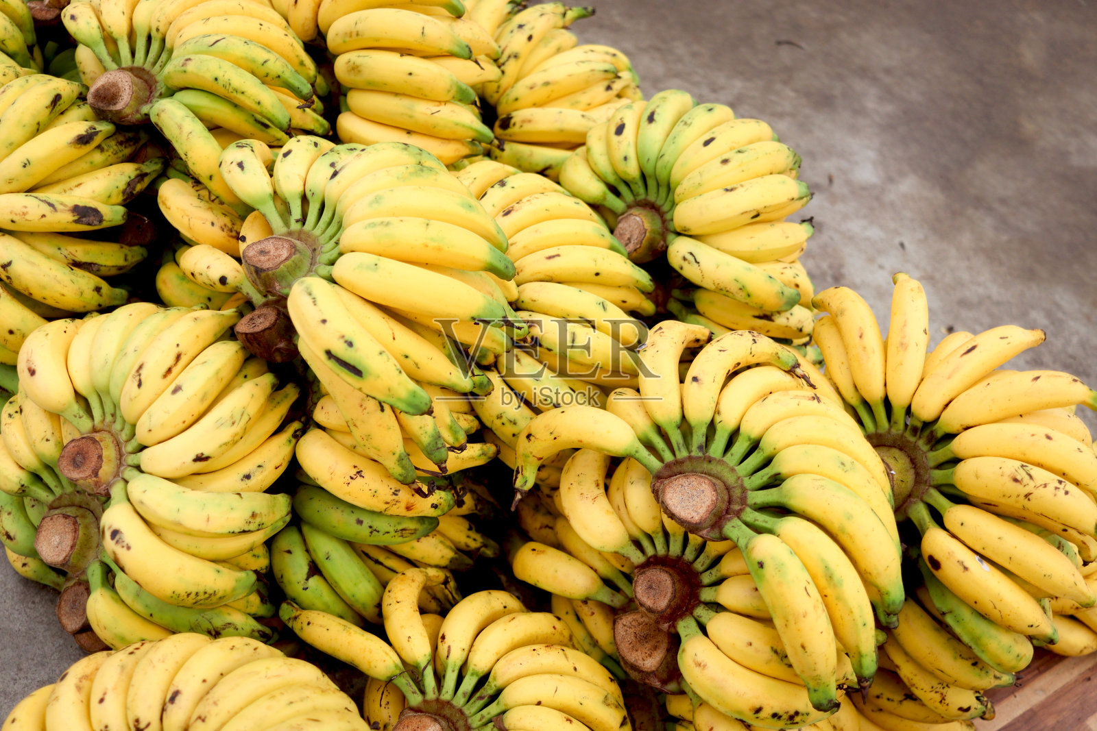 收获后，地板上有许多黄色的香蕉。新鲜的香蕉从农场运到市场出售。照片摄影图片