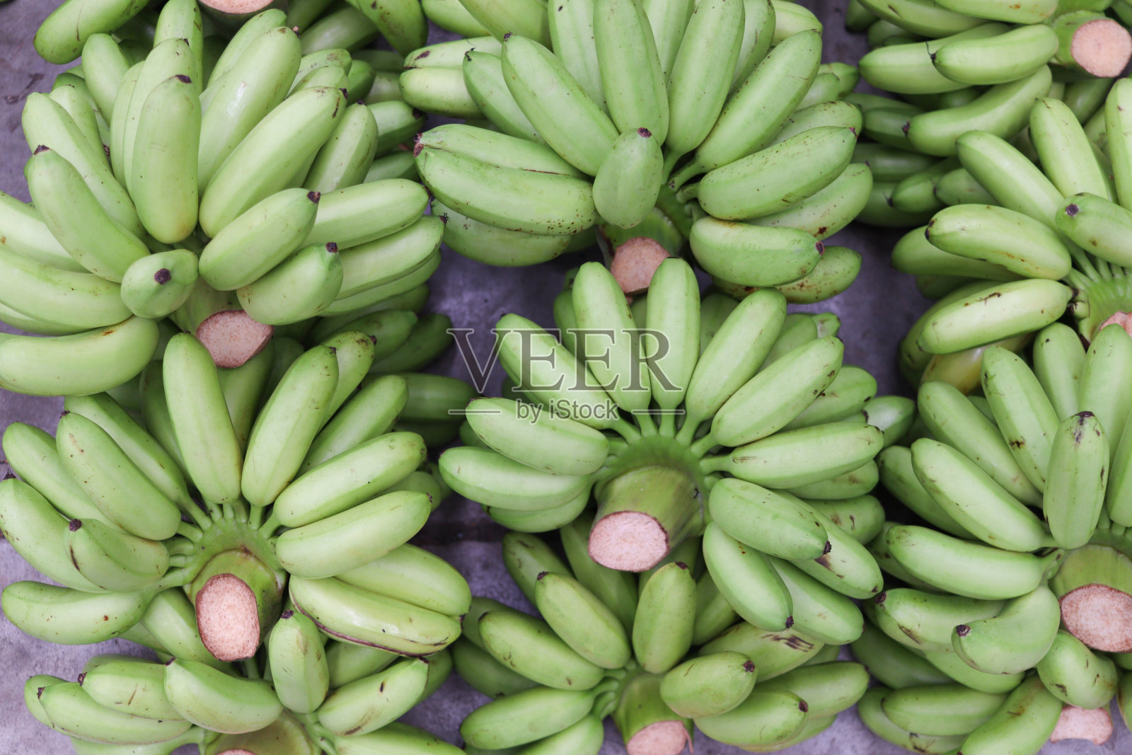 收获后，地板上有很多绿色的香蕉。新鲜的甜香蕉从农场被带到市场出售。照片摄影图片
