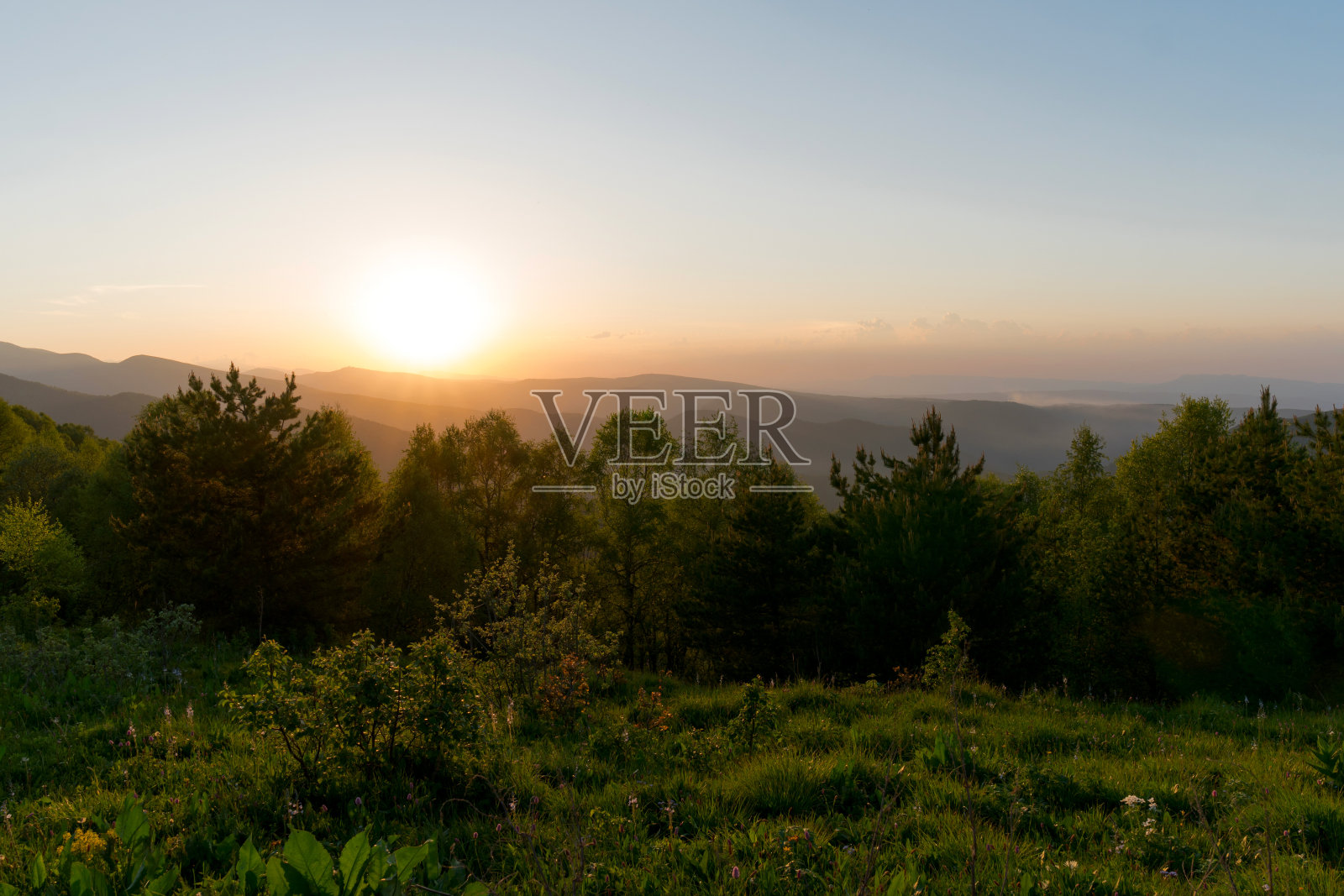 夕阳落在苍翠的山岗上。照片摄影图片