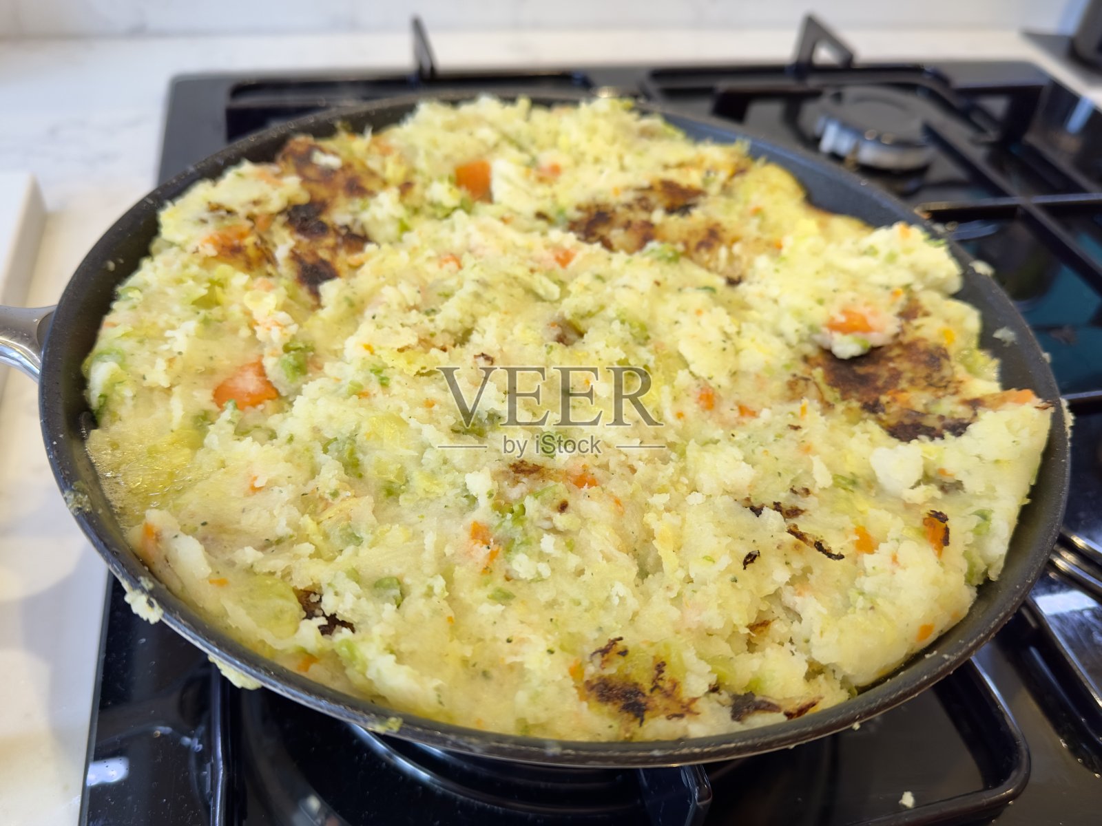 气泡和吱吱，这是一道传统的英国菜，用剩下的土豆和蔬菜做成，在煤气炉上的平底锅里煮。照片摄影图片