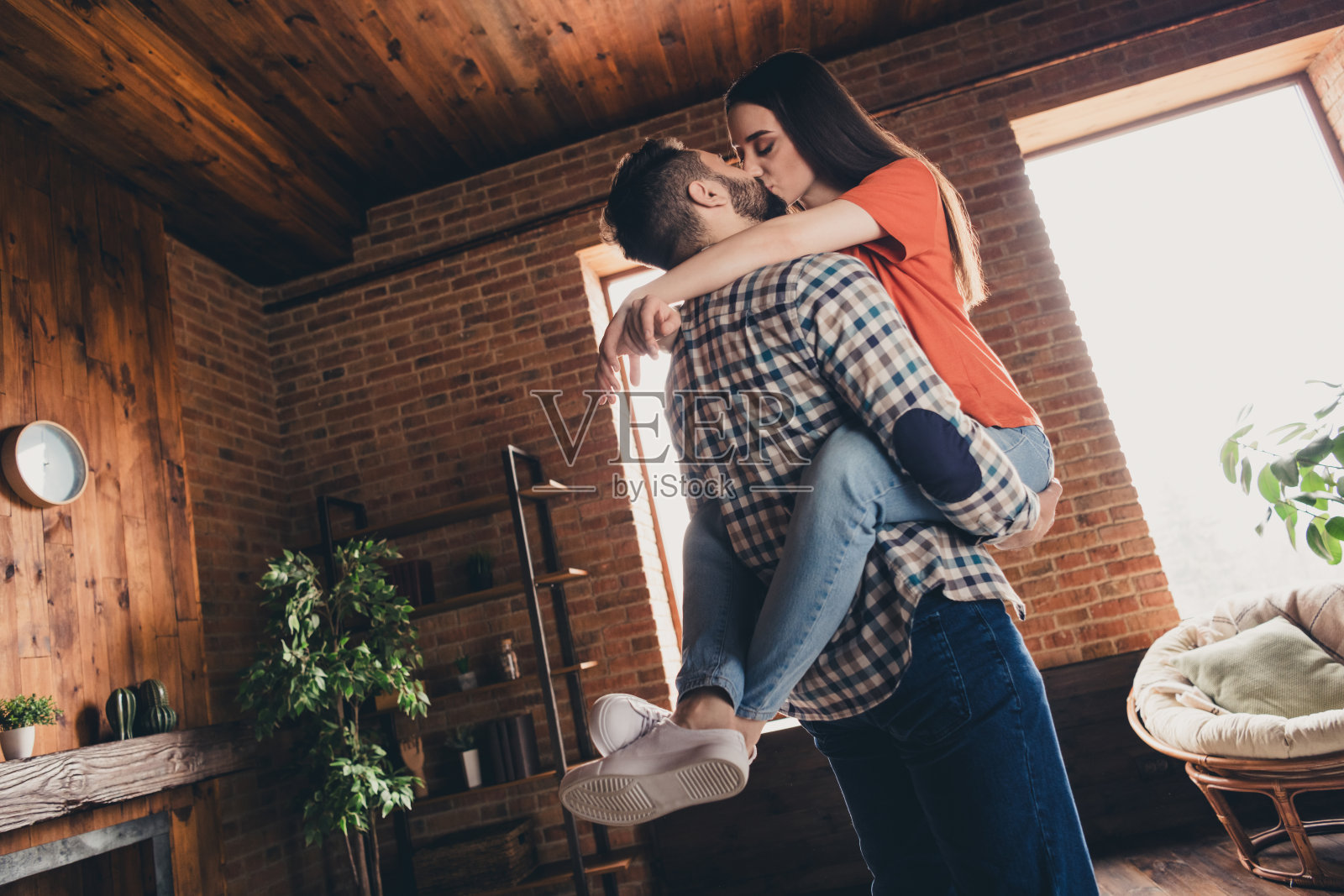 有吸引力的愉快的已婚年轻夫妇的照片，丈夫抱着妻子亲吻，花空闲时间搬新公寓，家，室内，室内照片摄影图片