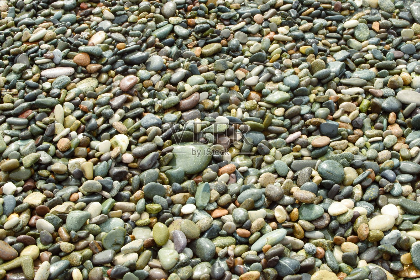 给沙滩上的鹅卵石上色。湿石背景。照片摄影图片