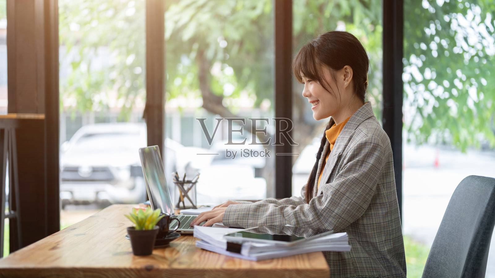 一个迷人的，积极的亚洲办公室职员正在她的办公桌上用笔记本电脑工作。照片摄影图片