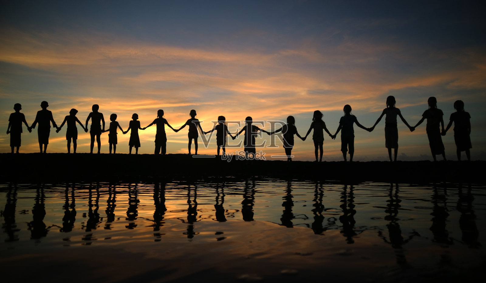 孩子们手牵着手站在夕阳下的天空照片摄影图片