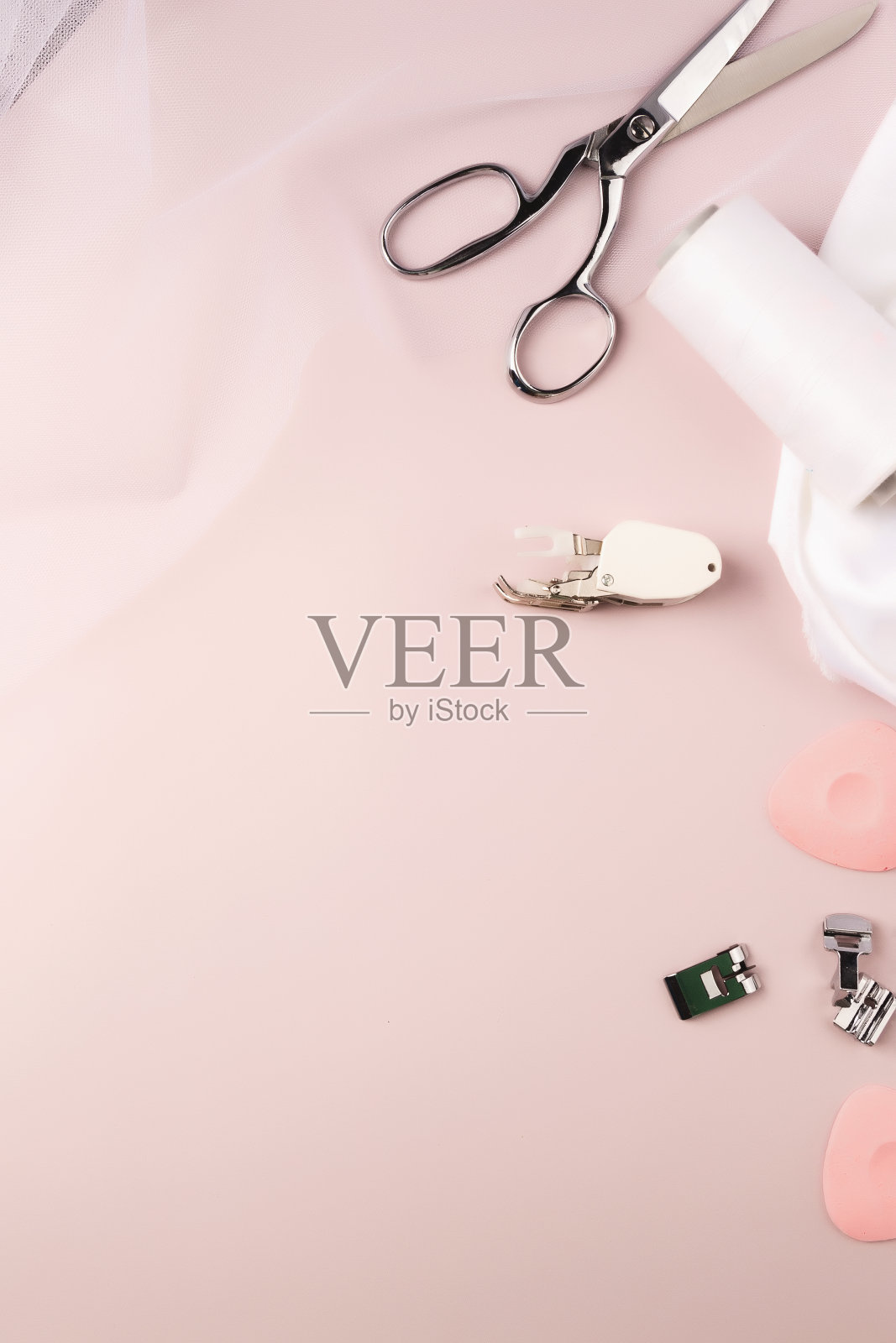 定制配件。白色绸缎或真丝织物，剪刀，粉笔在淡粉色的背景。女人爱好缝纫照片摄影图片