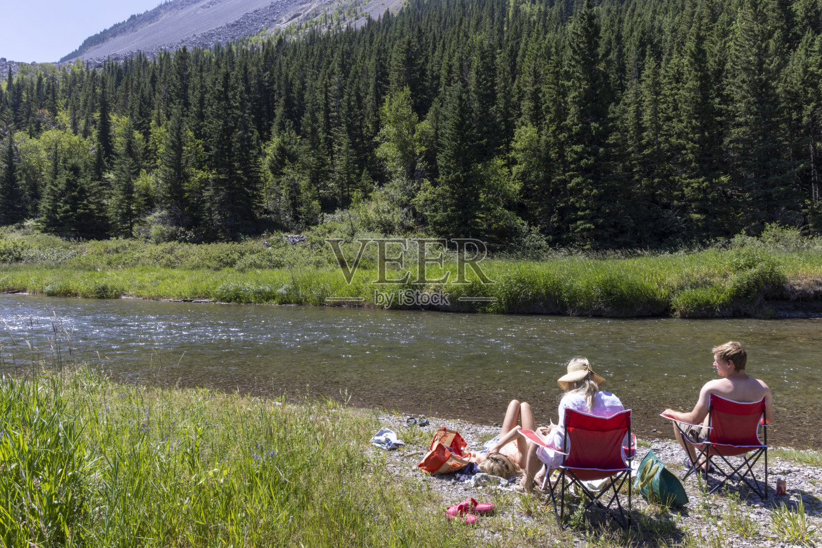 带着成年子女的家庭在森林的河岸上放松照片摄影图片