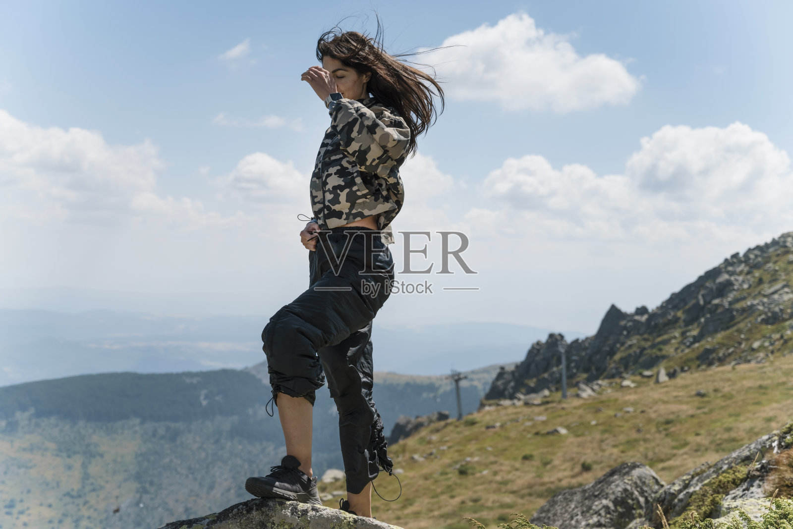 女人站在夏天山上的岩石上照片摄影图片