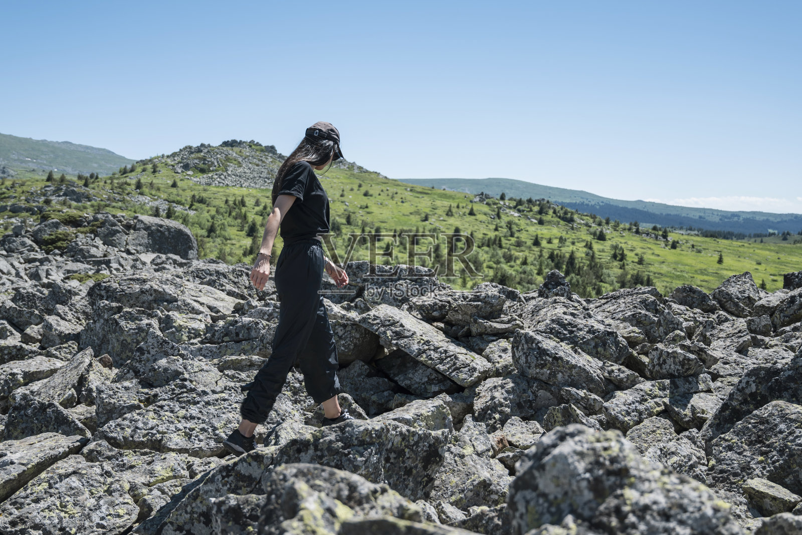 女人站在夏天山上的岩石上照片摄影图片