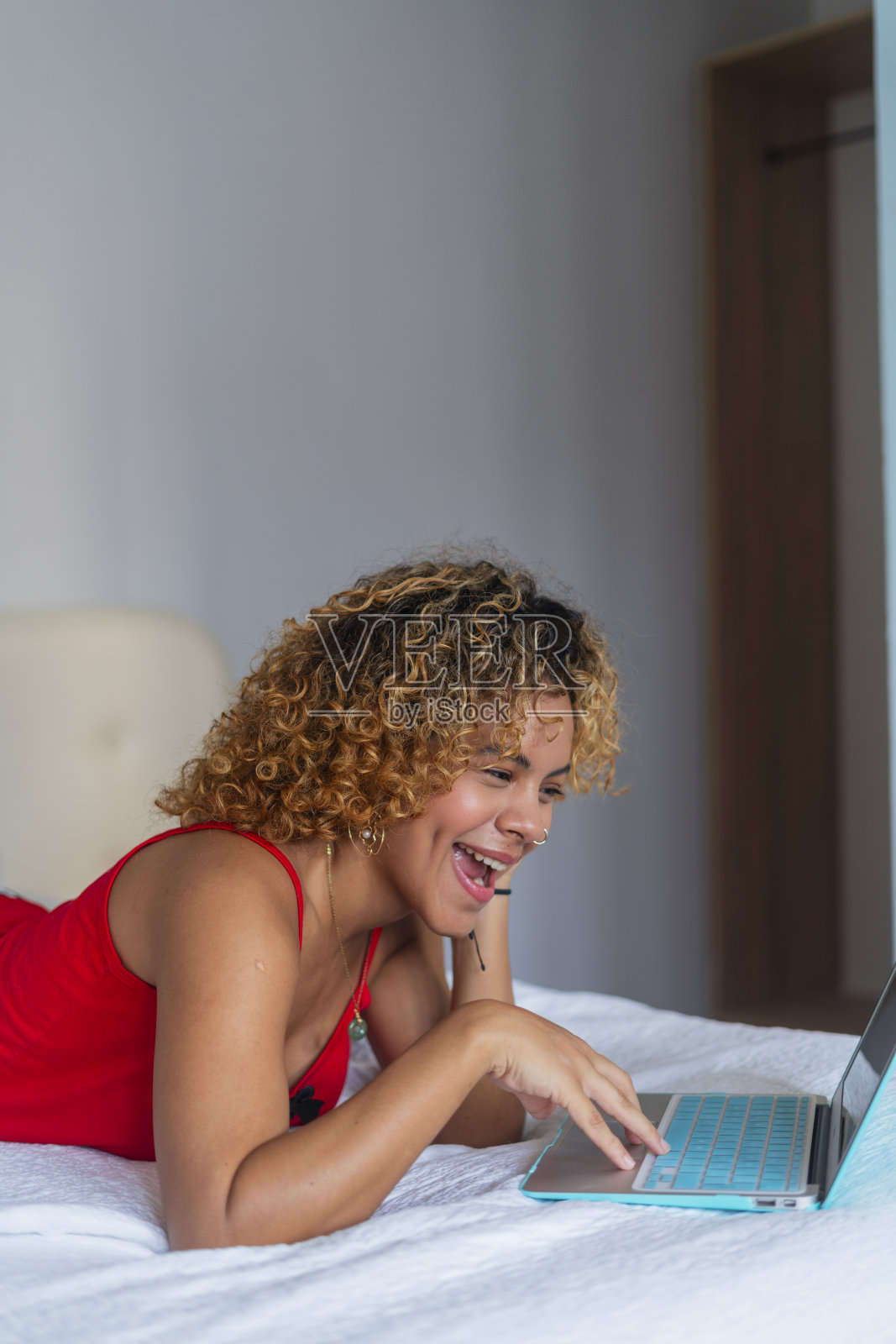 来自哥伦比亚卡塔赫纳的拉丁裔女子躺在酒店的床上，一边检查着她的笔记本电脑，一边穿着睡衣照片摄影图片