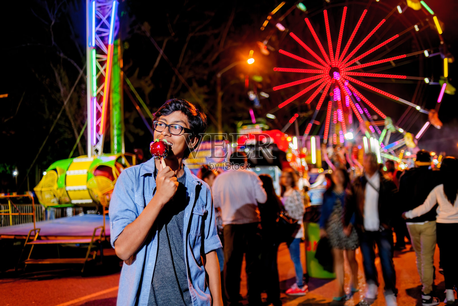 年轻人在晚上逛游乐园。照片摄影图片
