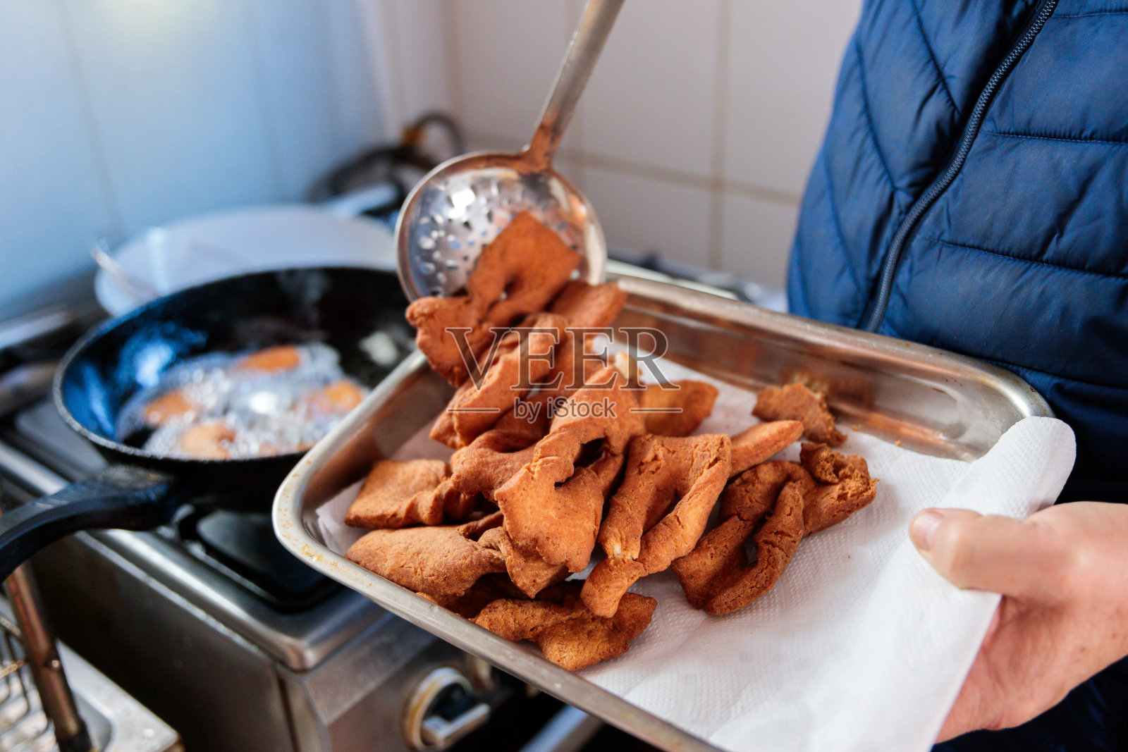在自家厨房里，一个拉丁男人用手在平底锅里煎着一种深受智利人喜爱的甜酥皮照片摄影图片