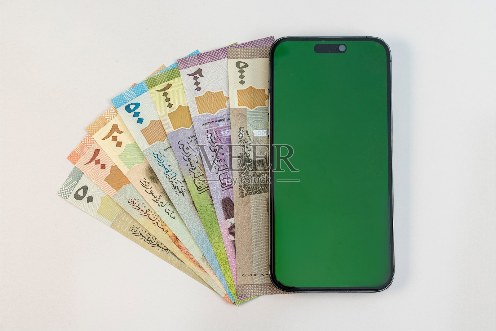 叙利亚纸币和智能手机与绿色空白屏幕隔离在白色背景照片摄影图片
