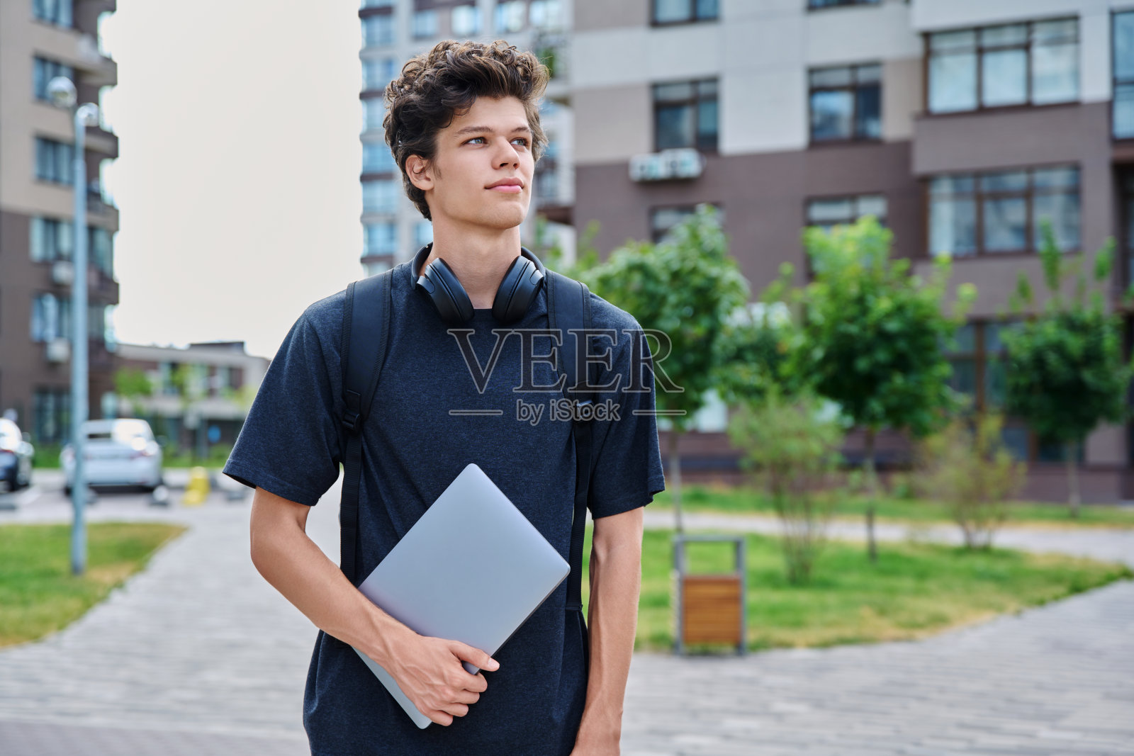 肖像年轻男大学生背包笔记本电脑，户外城市背景照片摄影图片
