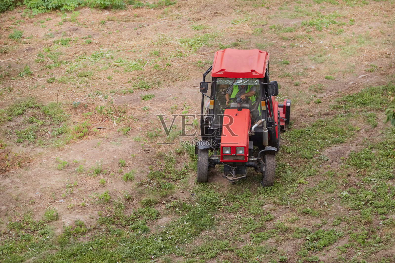 开着割草机的拖拉机整齐地清理着大片田野上的草。照片摄影图片