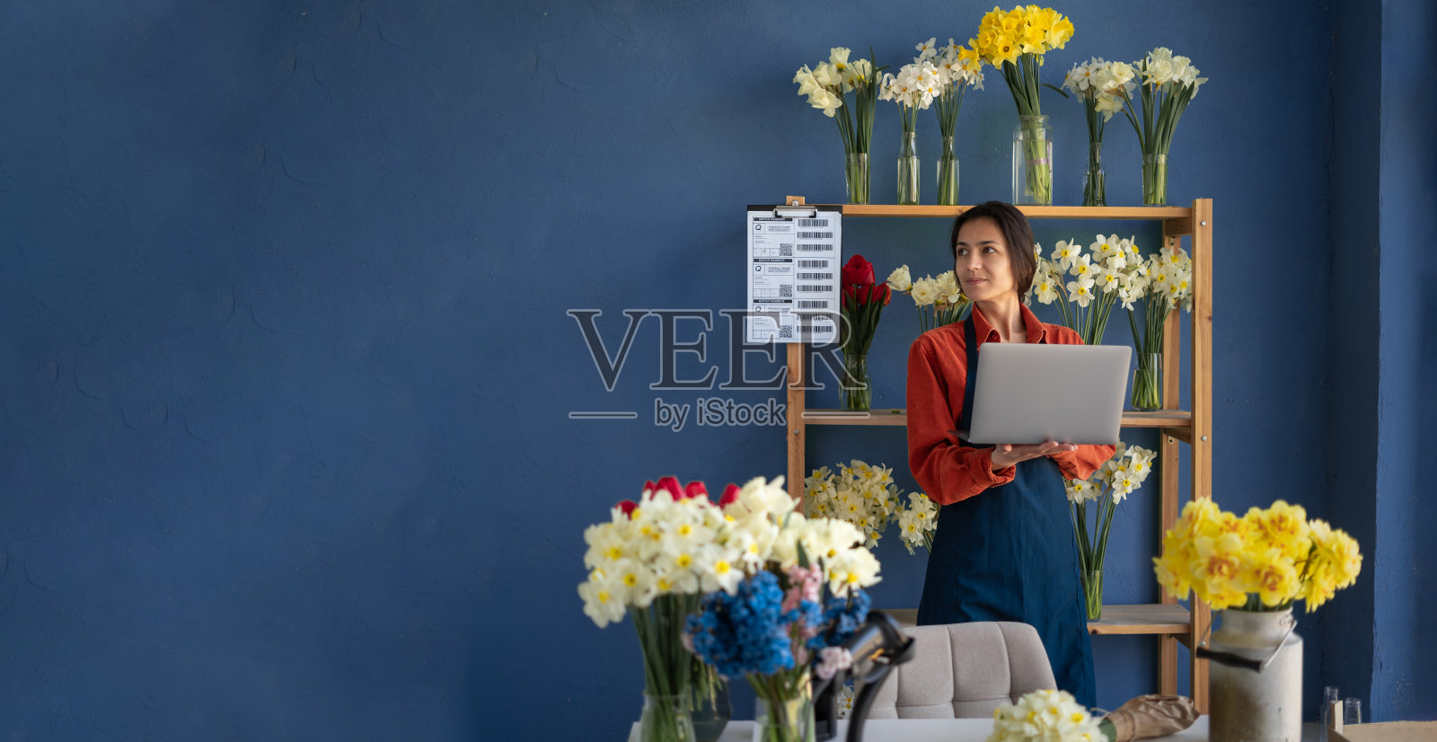 在花店工作的女花商用笔记本电脑寻找文字空间。小型企业和鲜花配送的概念。横幅照片摄影图片