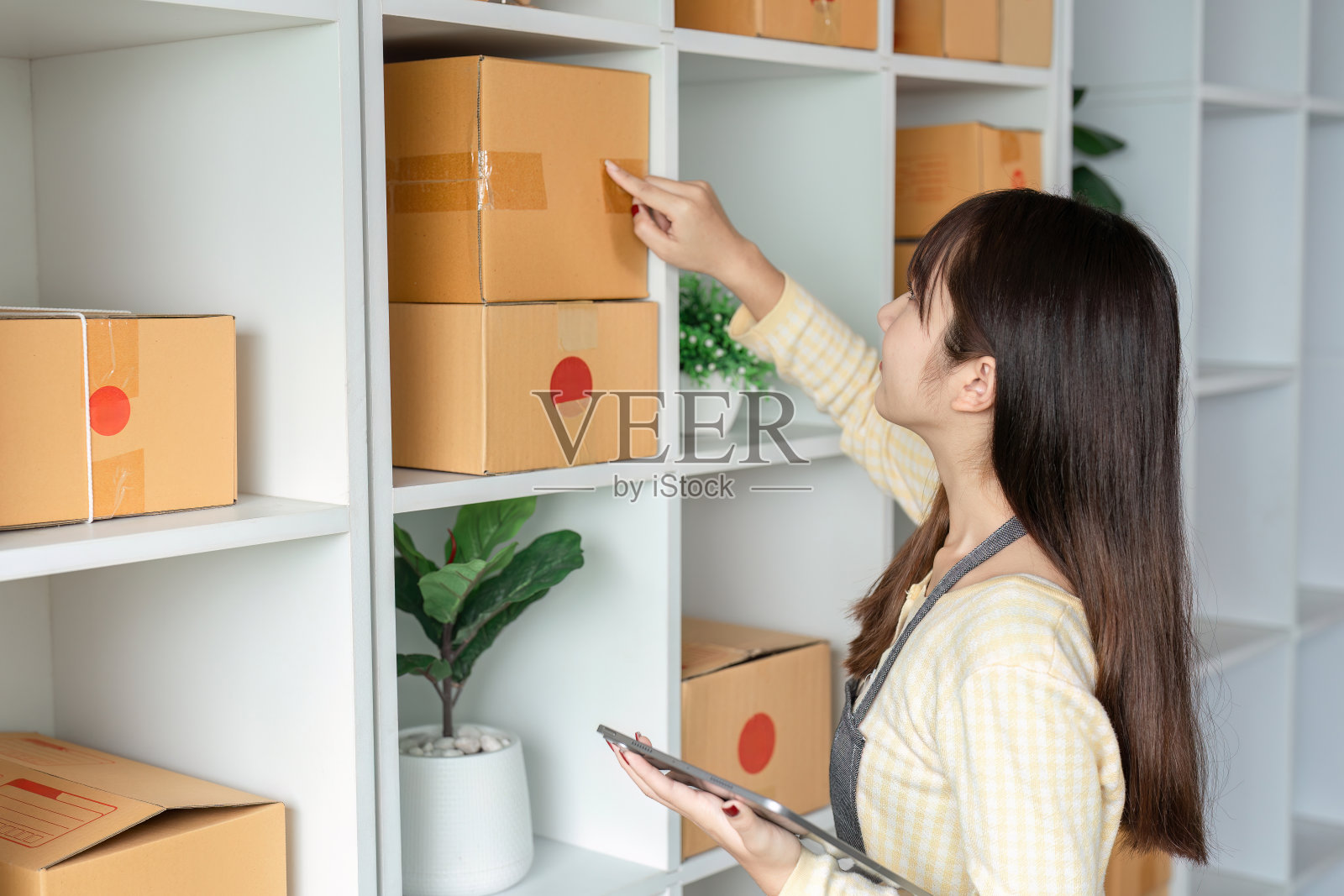 年轻女性在现代家庭办公环境中管理在线订单和库存照片摄影图片