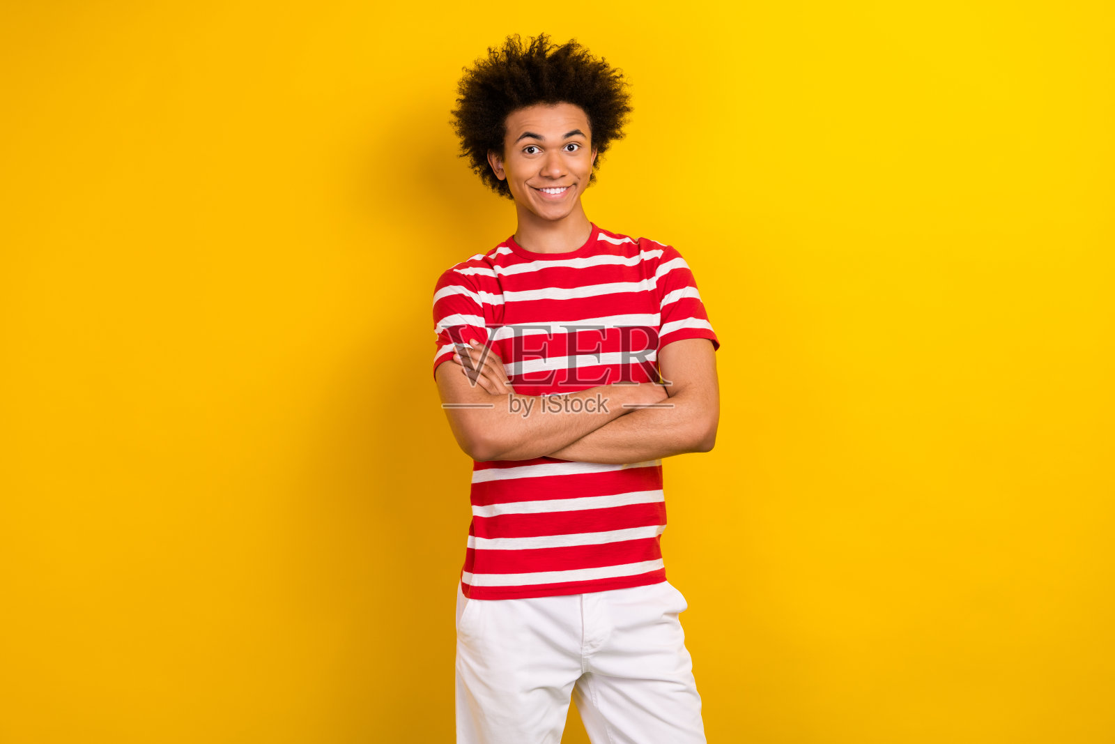 照片中的好人工人双手合抱牙齿微笑着穿着条纹衬衫白裤子孤立的黄色背景照片摄影图片