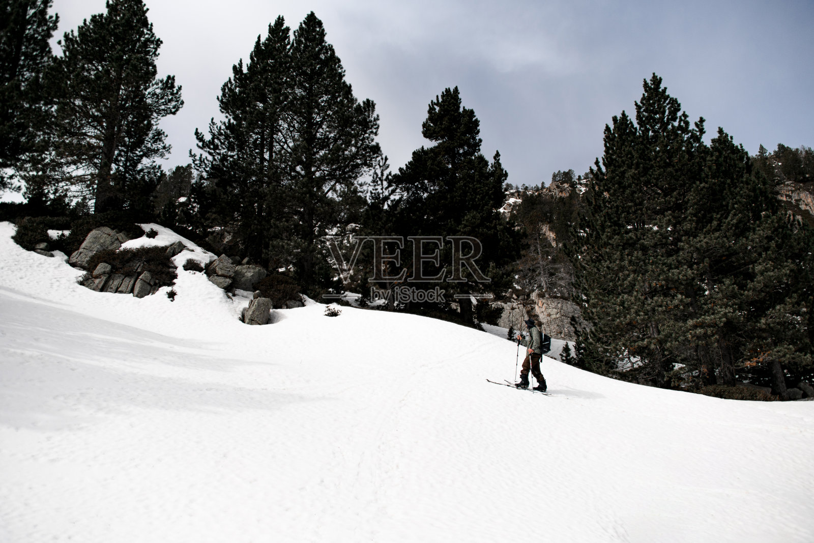 年轻的滑雪者自信地站在滑雪板上滑下平缓的斜坡照片摄影图片