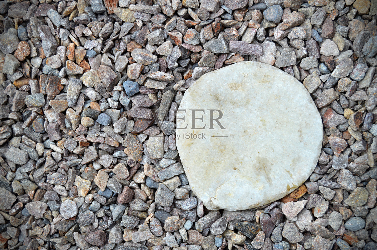 灰色的彩色鹅卵石或砾石水平照片与各种大小不均匀的石头，使粗糙的乡村背景壁纸与一些彩色的小石头和一个圆形的白色大理石圆圈作为标签的复制空间照片摄影图片
