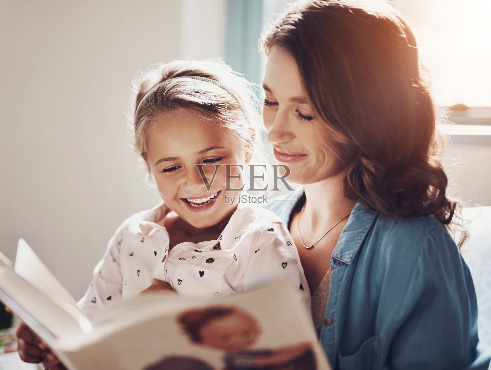 母亲，女孩，兴奋地在家里讲童话故事，儿童发展和教育。家庭中，父母和孩子用微笑学习，用书本阅读获取知识和信息照片摄影图片