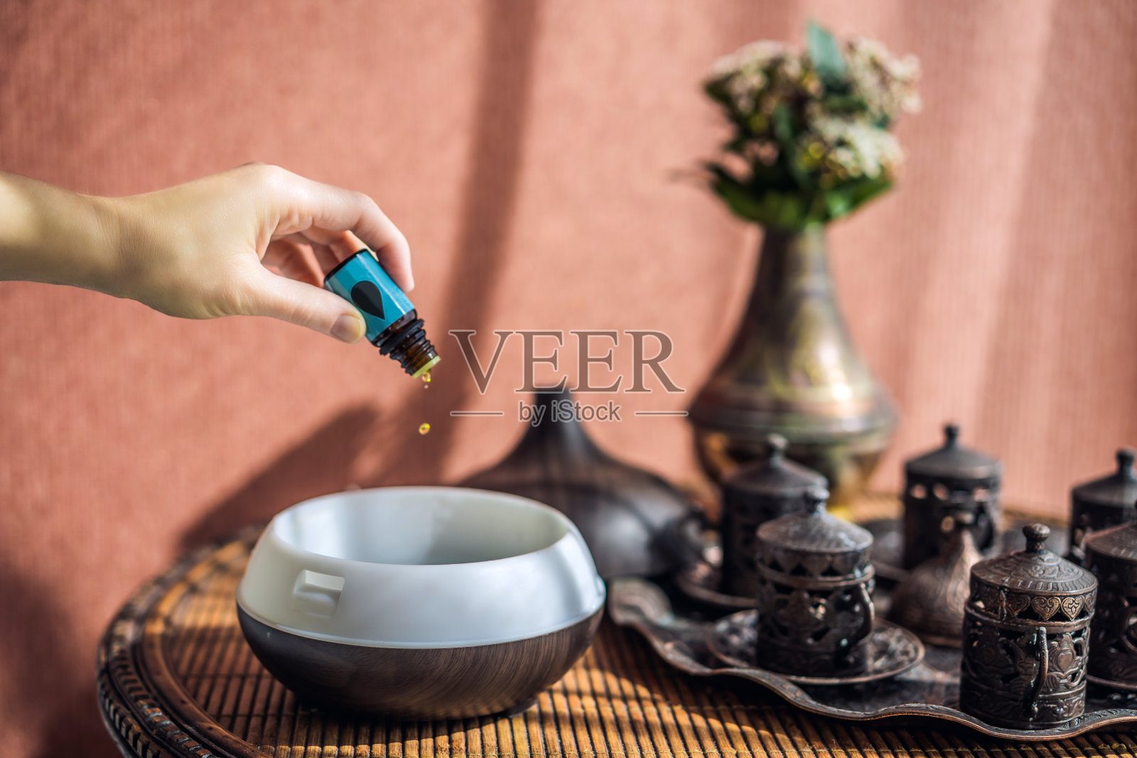 女士在桌子上往香薰器里加精油照片摄影图片