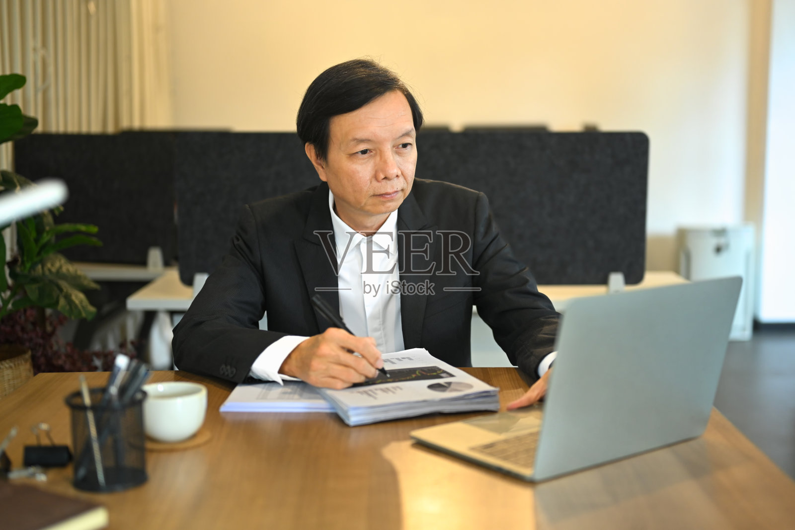 专业成熟的商人使用笔记本电脑，在木桌上分析财务报告照片摄影图片