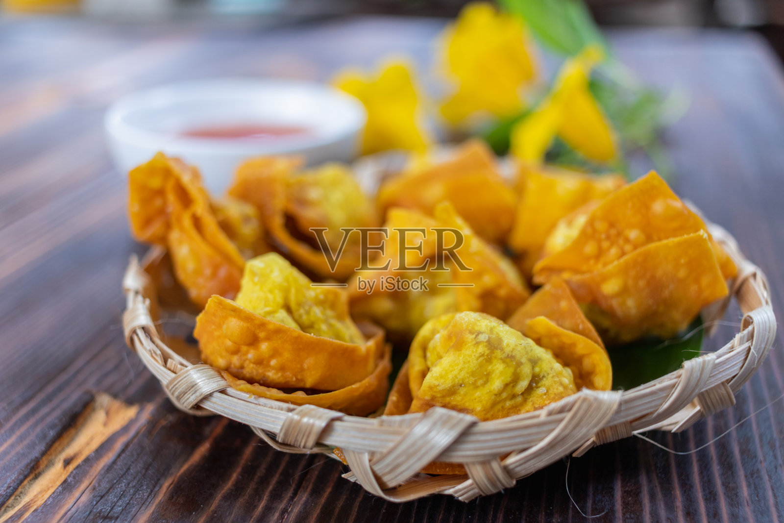 包着鸡肉、蔬菜和香料的脆皮饺子放在餐厅内木桌上的白色盘子里。煎饺因其美味而广受欢迎。照片摄影图片