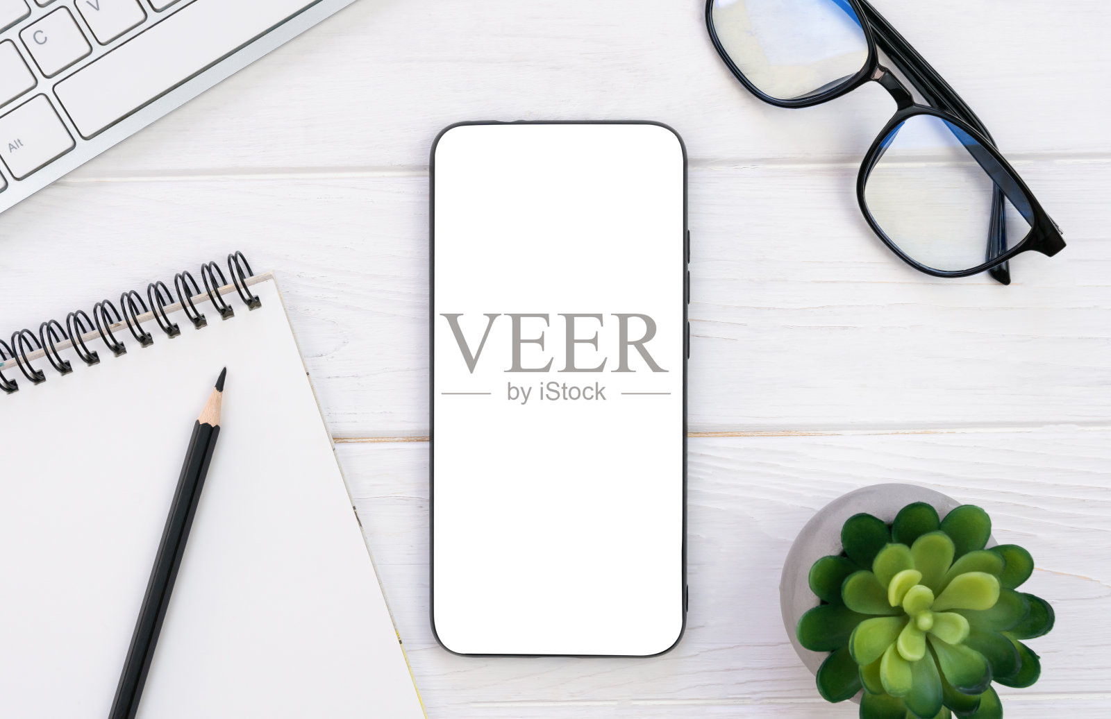 工作场所，在木桌上放上空白的记事本、铅笔、眼镜和智能手机。模型。Flatlay。前视图。副本的空间。照片摄影图片