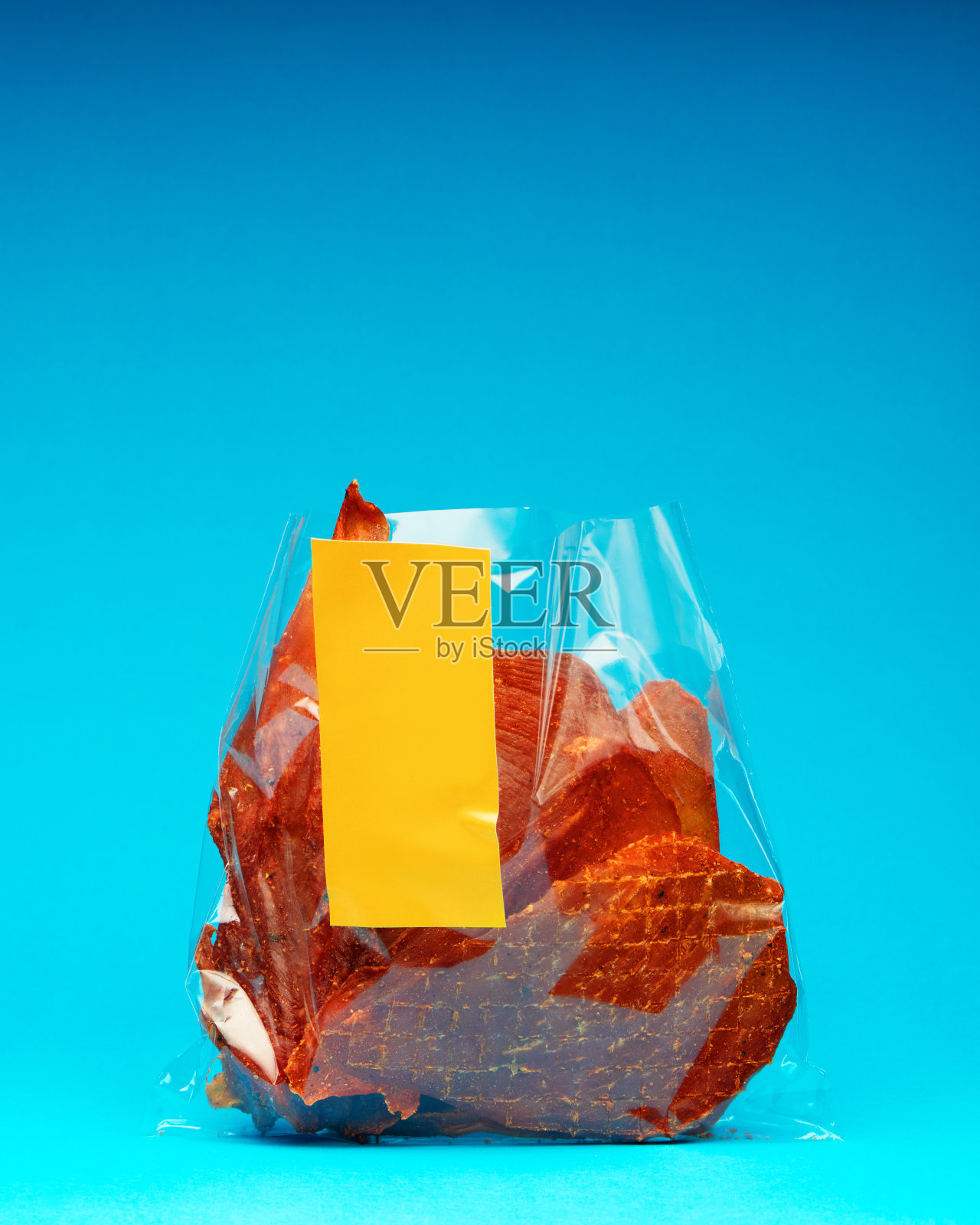 打开肉干包装，黄色标签，亮蓝色背景上的空白空间照片摄影图片