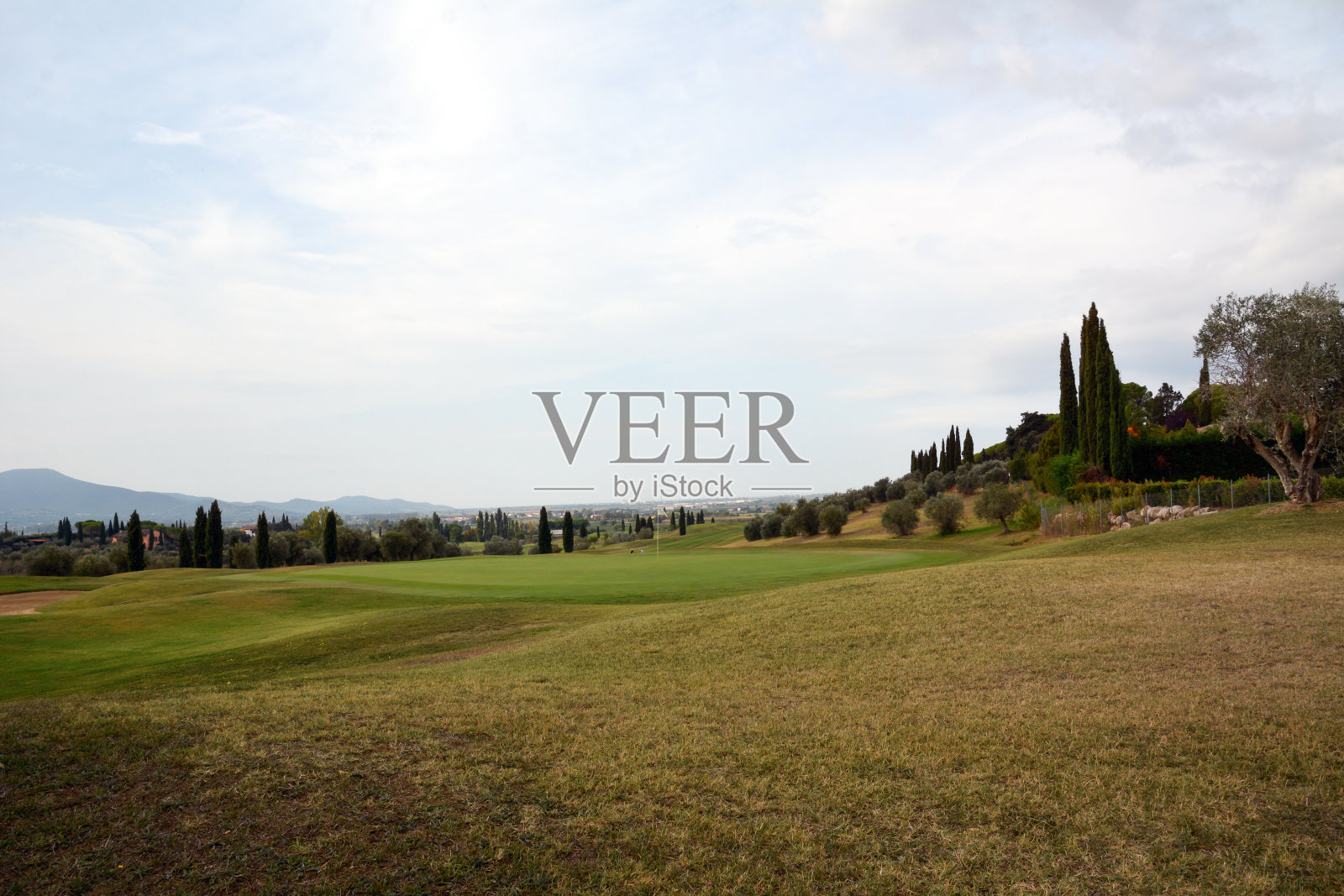 远处有草坪和山脉的高尔夫球场。草被剪短了照片摄影图片