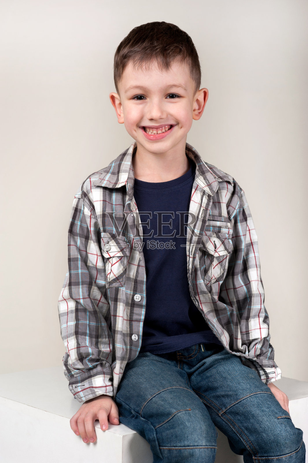 小白种男孩坐在箱子上，孤立在摄影棚的背景下。快乐的童年，教育，情绪，表情照片摄影图片