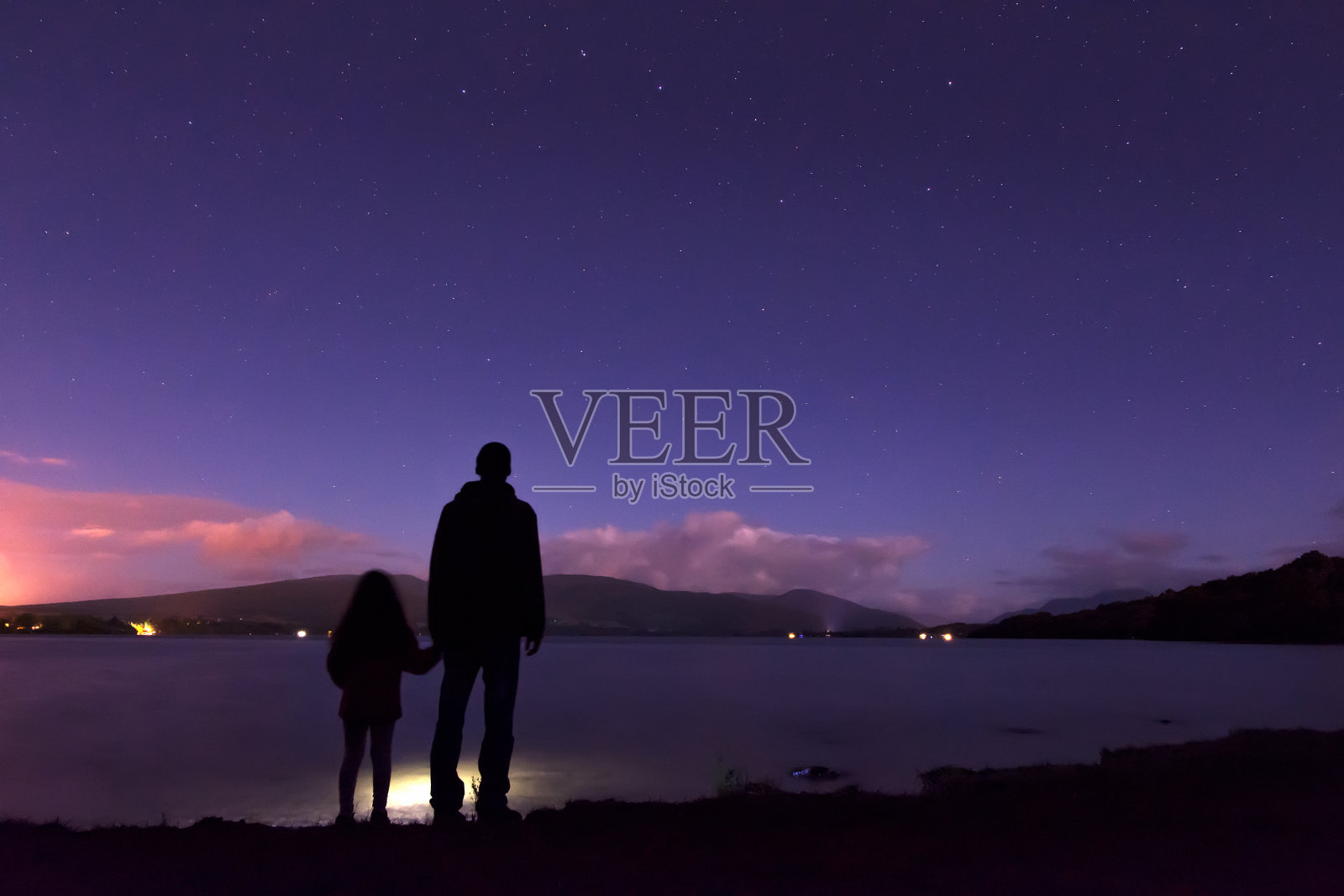 父亲和女儿站在湖边，背对天空的夜景照片摄影图片