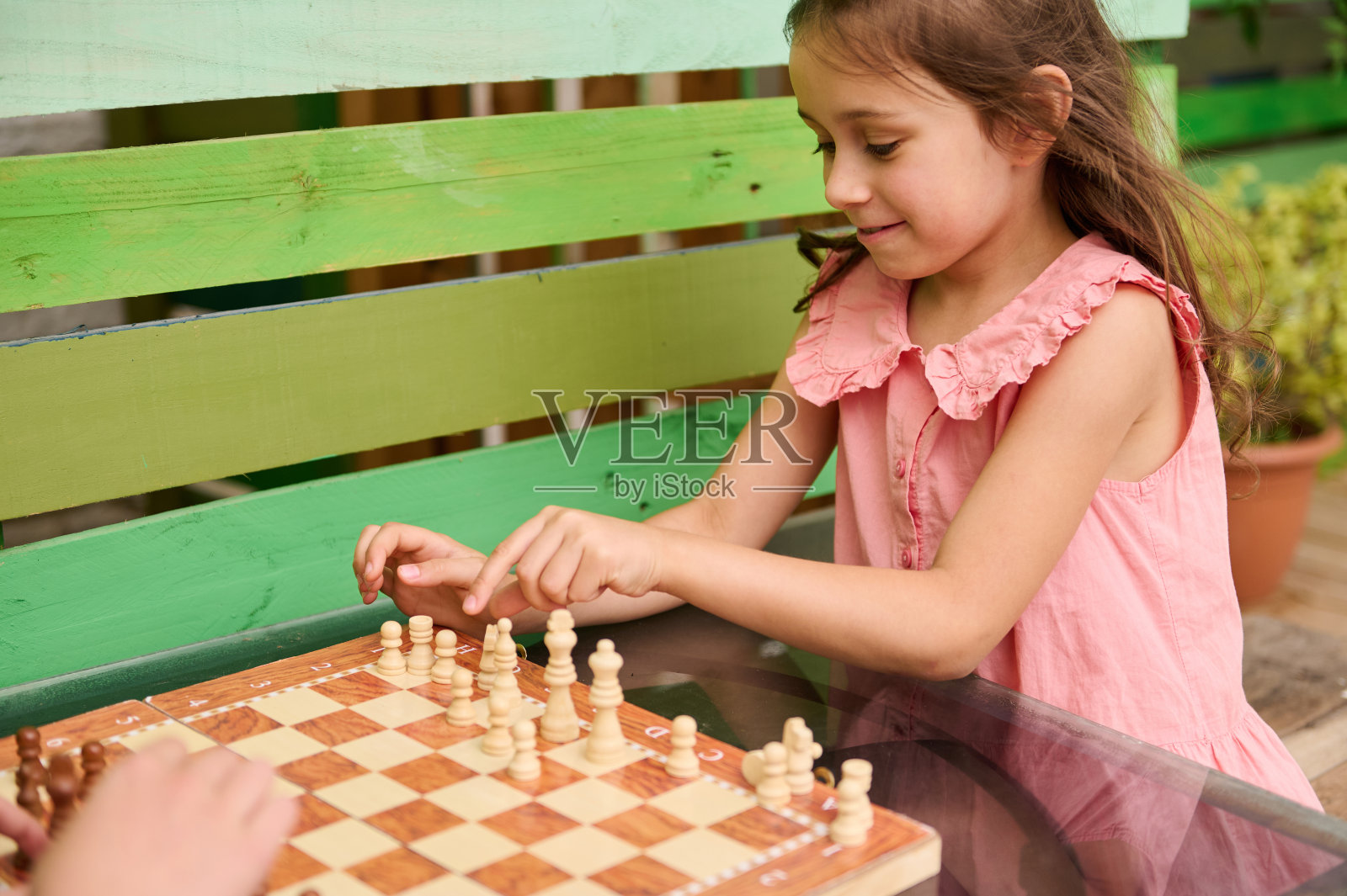 小女孩穿着粉红色的裙子在户外下棋照片摄影图片