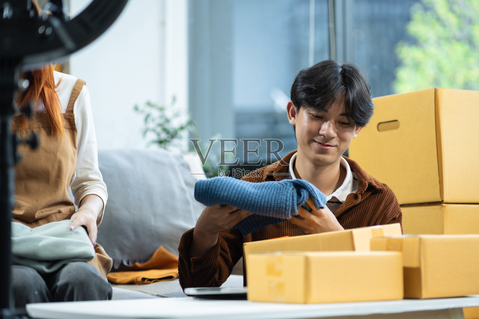 一对夫妇开始做小生意。夫妇在家里在线直播销售服装产品。照片摄影图片
