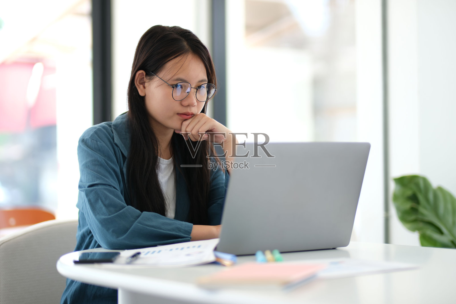 一位女士坐在办公桌前，笔记本电脑摆在她面前照片摄影图片